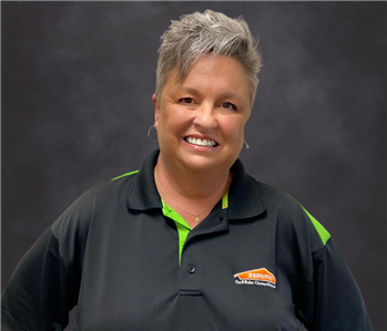 Woman in black SERVPRO shirt stands smiling